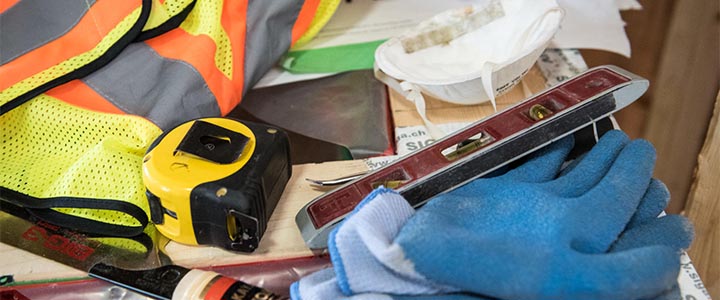 Construction tools - gloves, mask, safety, vest, tape measure, and leveler sitting on a table