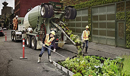 Construction workers using a large truck and rake to make a food garden